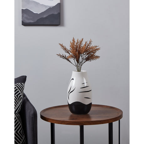 Yuzawa ceramic vase with glossy white body, wavy black base band, and black brush-stroke details, holding dried foliage on a wooden side table in a living room.