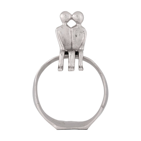 Zadiwin Figurines in silver aluminium, showing two simplified figures with rounded heads leaning together in a kiss, seated with legs over an open ring base, on a plain white background.