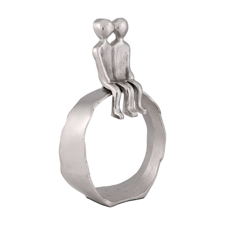 Zadiwin Figurines in silver aluminium, a sculpture of two simplified figures with heads leaning together, legs dangling over an open ring base, shown on a plain white background.