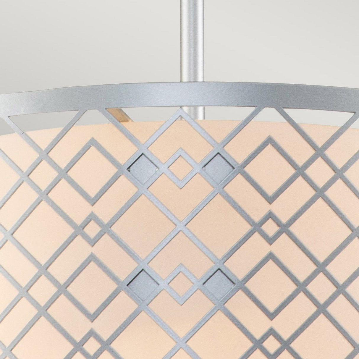 A close-up of the Ziggy 2 Light Duo-Mount Medium Pendant/Semi-Flush in Lacquered Silver highlights its contemporary design with a geometric metal lattice. The interlocking diamond and square patterns cast soft, warm light through a frosted glass or fabric diffuser behind the lattice, embodying adaptable lighting at its finest.