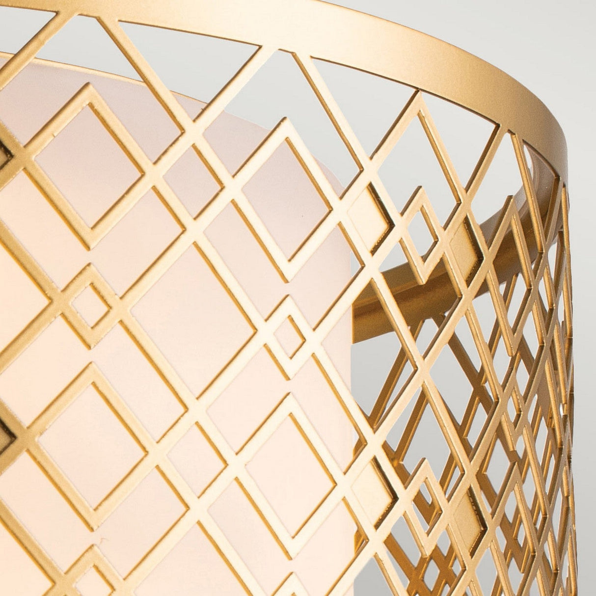 A close-up showcases the geometric lattice pattern in lacquered gold, with interlocking diamonds and squares. Set against a soft, light background, it embodies a contemporary style similar to the Ziggy 2 Light Medium Flush - Lacquered Gold.