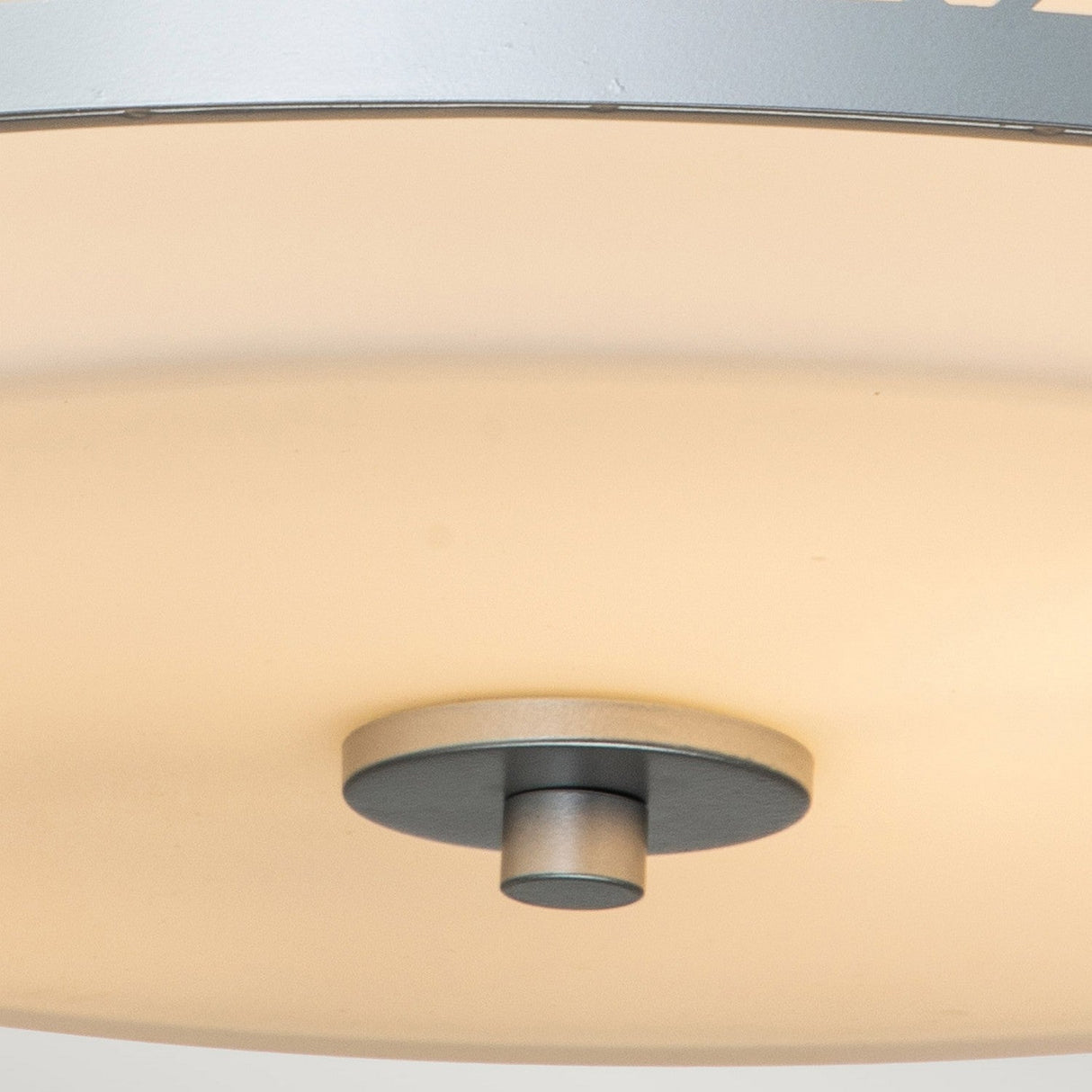 Close-up of the Ziggy 2 Light Medium Flush in lacquered silver, showcasing an opal glass shade. The fixture casts a soft and diffused light, creating a warm glow.