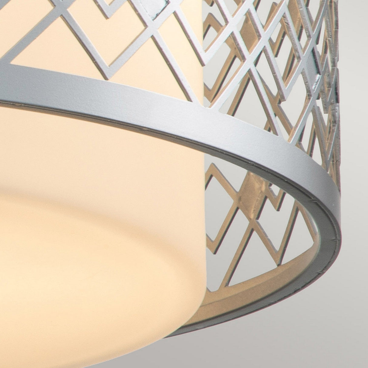 Close-up of the Ziggy 2 Light Medium Flush, showcasing its opal glass shade adorned with a geometric diamond-patterned metallic lattice. The lacquered silver finish accentuates its modern and elegant appeal.