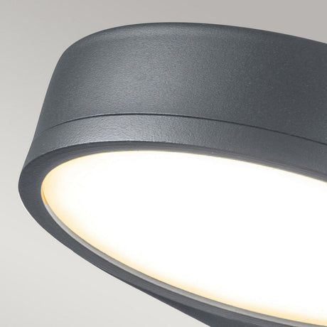 Close-up of the Zola Outdoor LED Wall Light in grey, showcasing its circular design crafted from weather-resistant stainless steel. The light emits a soft, warm glow against a neutral background, making it an ideal choice for enhancing any contemporary space.