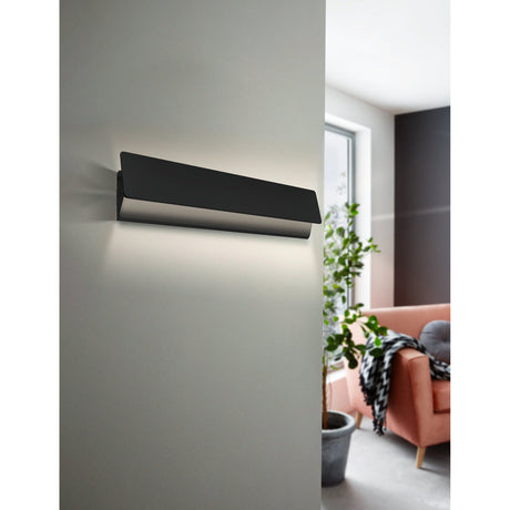 Zubialde LED wall light in black and white, slim rectangular aluminium and steel design mounted on a grey wall, casting warm white uplight and downlight in a living room setting.